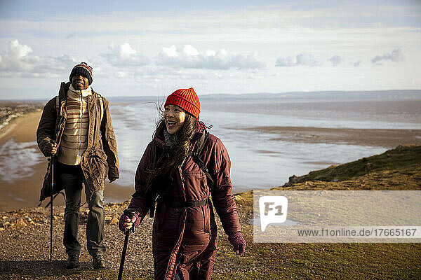 Wandererpaar auf sonniger Klippe über dem winterlichen Meeresstrand