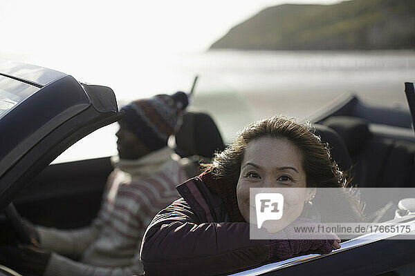 Portrait glückliche Frau im Cabrio am Strand