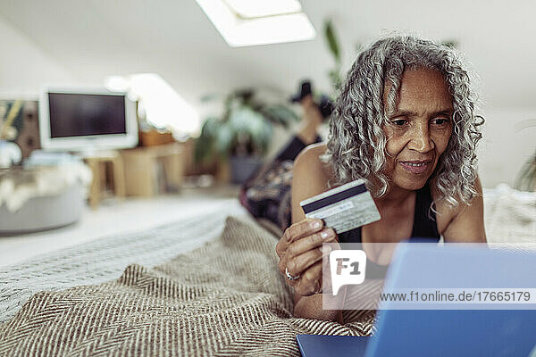 Ältere Frau mit Kreditkarte beim Online-Shopping am Laptop