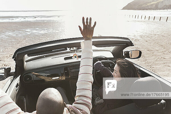 Unbeschwertes Paar fährt im Cabrio am sonnigen Strand