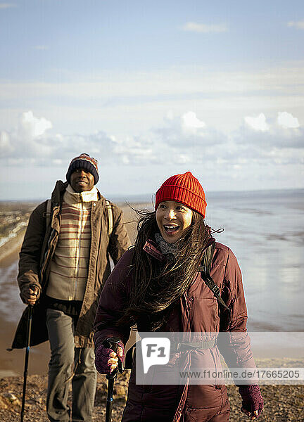 Glückliches Wandererpaar auf sonniger Klippe über dem Meer