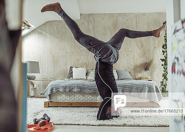 Senior man practicing headstand on bedroom rug