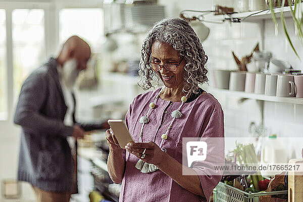 Ältere Frau benutzt Smartphone in der Küche