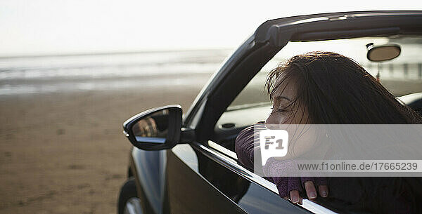 Serene woman in convertible on beach