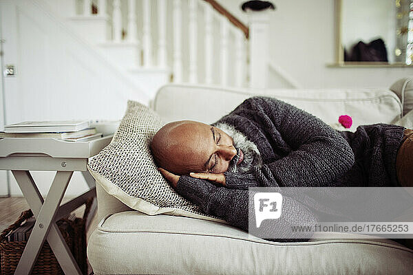 Tired mature man sleeping on living room sofa