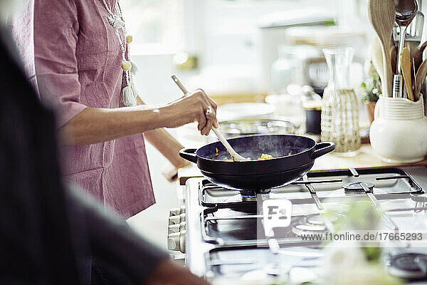 Woman cooking in wok on kitchen stove