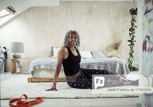 Porträt einer selbstbewussten älteren Frau  die sich auf dem Boden eines Schlafzimmers streckt