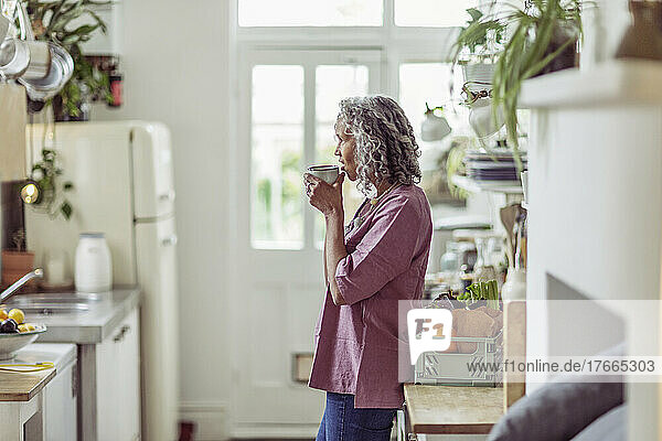 Nachdenkliche ältere Frau trinkt Kaffee in der Küche