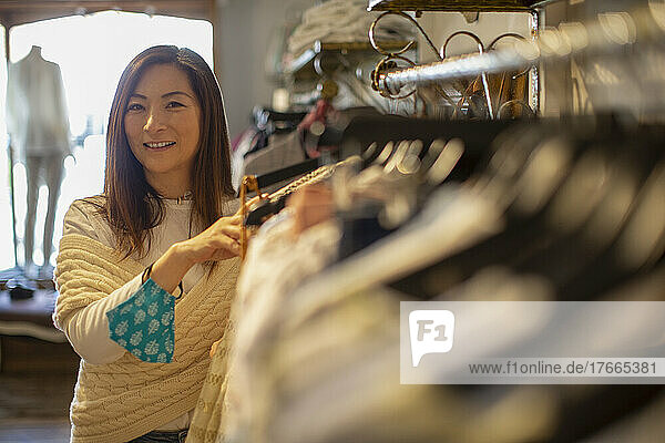 Portrait confident female shop owner with face mask in clothing shop