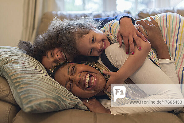 Portrait glückliche verspielte Mutter und Kinder auf Sofa