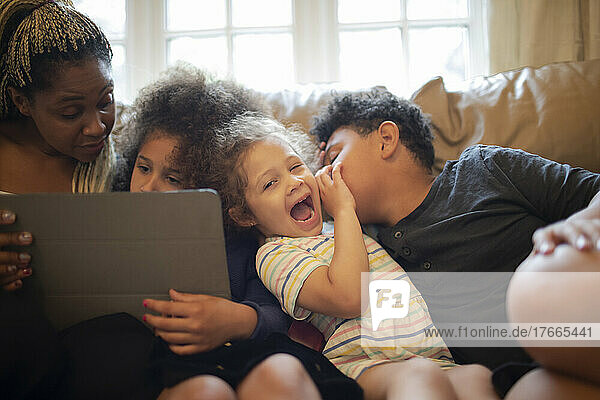 Mutter und Kinder mit digitalem Tablet auf dem Sofa