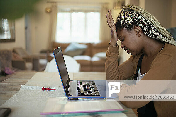 Frustrierte Frau arbeitet von zu Hause aus am Laptop