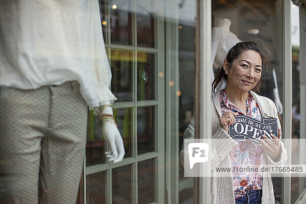Porträt glückliche Ladenbesitzerin mit offenem Schild vor der Boutique