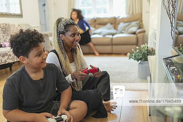 Mutter und Sohn spielen ein Videospiel auf dem Wohnzimmerboden