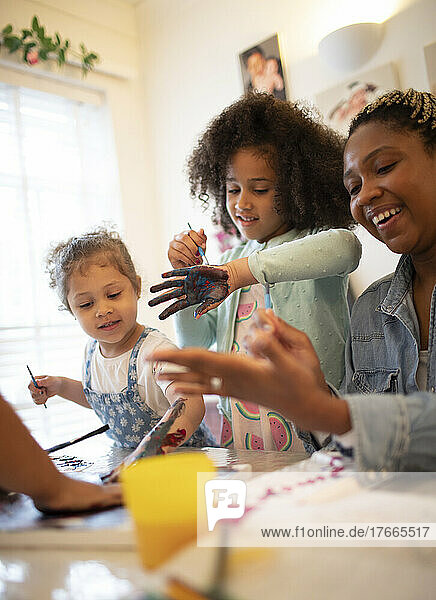 Glückliche Mutter und Töchter malen mit den Fingern