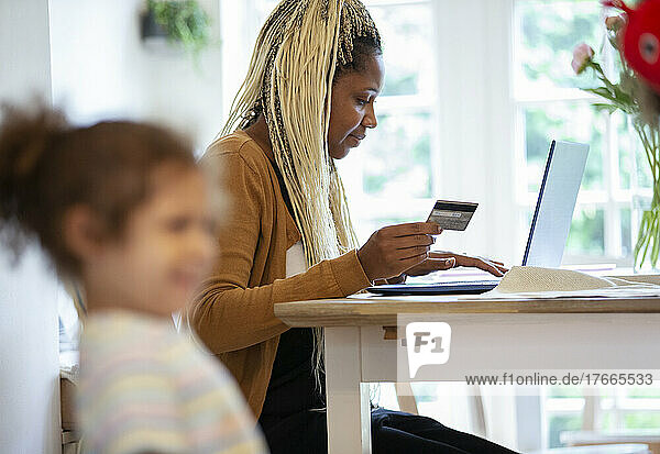 Frau mit Kreditkarte bezahlt Rechnungen am Laptop