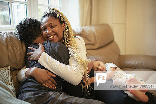 Happy mother hugging son on living room sofa