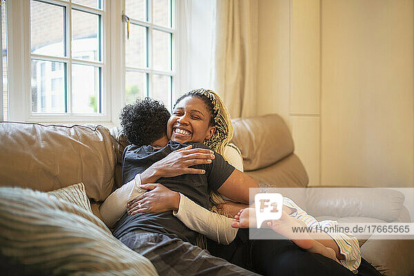 Happy mother and son hugging on living room sofa