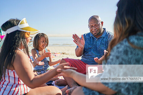 Family playing clapping game on sunny beach