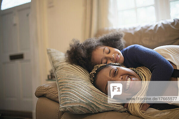 Happy mother and daughter cuddling on living room sofa
