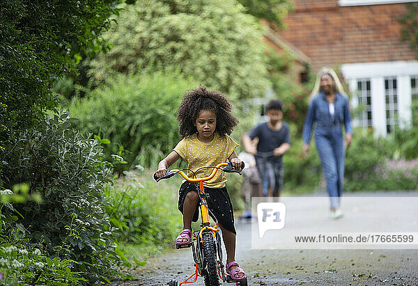 Girl riding bicycle in driveway