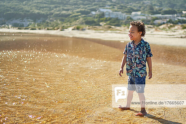 Happy boy with Down Syndrome wading in ocean surf on sunny beach