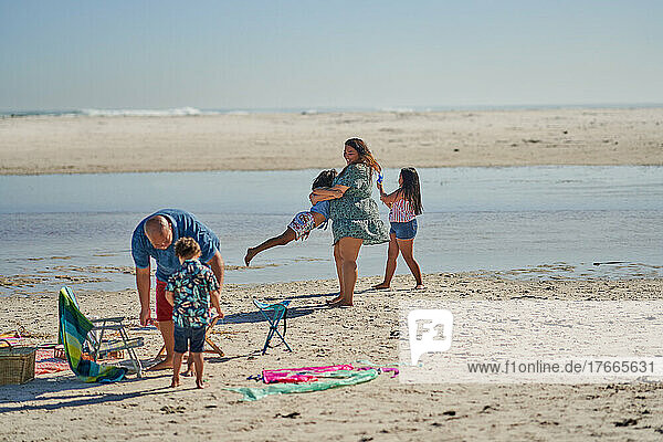 Family playing on sunny ocean beach
