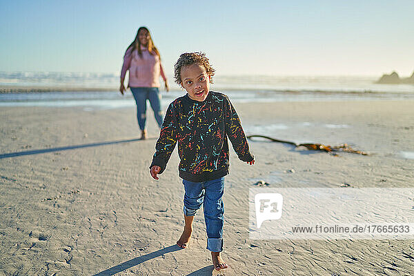 Portrait cute boy with Down Syndrome walking on sunny beach