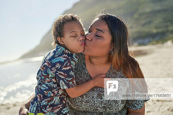 Happy  affectionate mother and son kissing on sunny beach