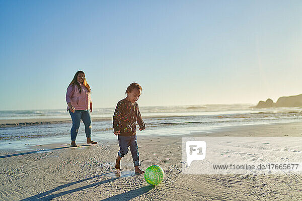 Mother and son with Down Syndrome playing with soccer ball on beach