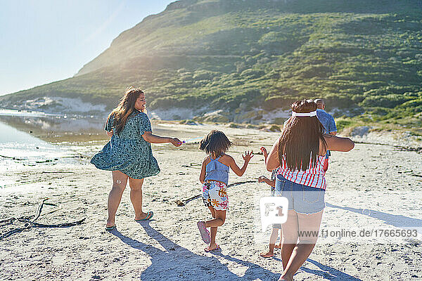 Happy family running on sunny summer beach