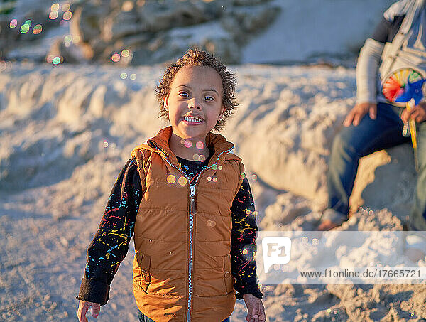 Portrait cute boy with Down Syndrome watching bubbles on beach