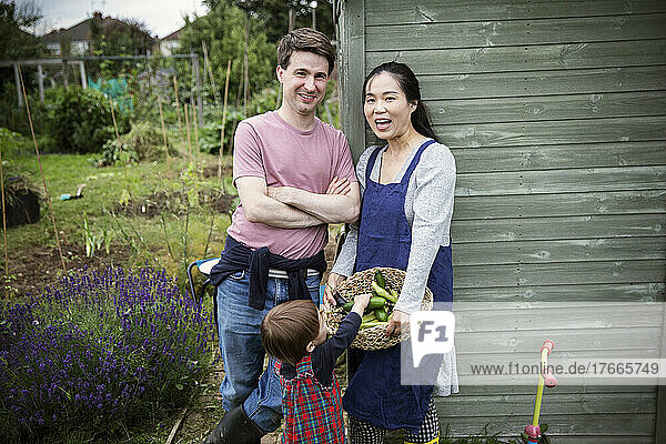 Portrait happy family with harvested vegetables in garden