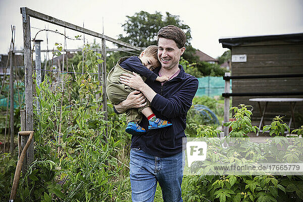 Happy father holding toddler son in garden
