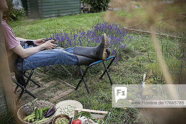 Man relaxing in garden with harvested vegetables