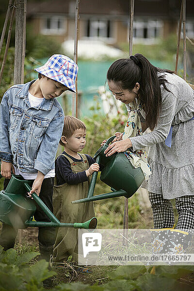 Mother and sons with watering cans in garden