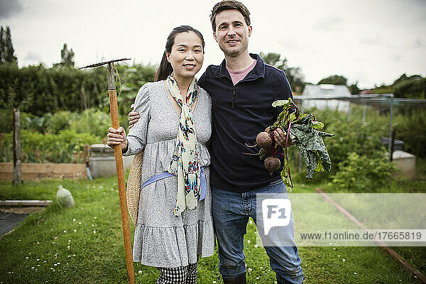 Portrait happy couple with harvested beets in garden