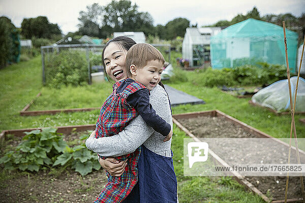 Happy mother and toddler son in vegetable garden