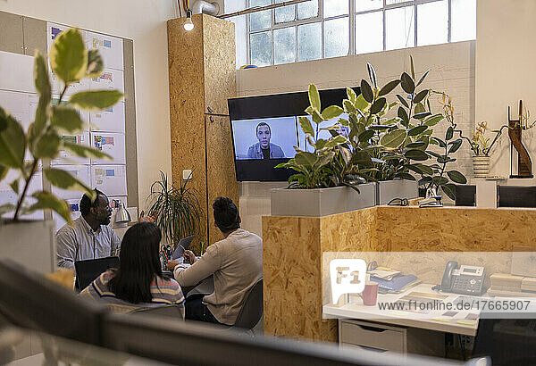 Building designers video chatting with colleagues on screen in office