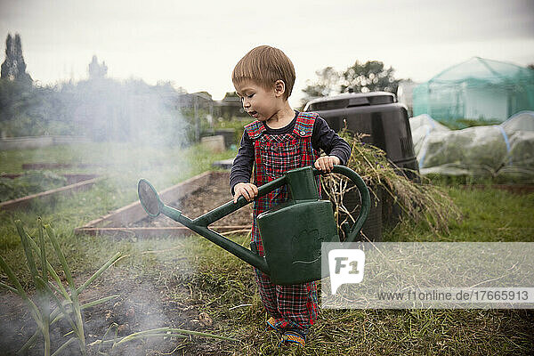 Cute toddler boy with watering can in garden