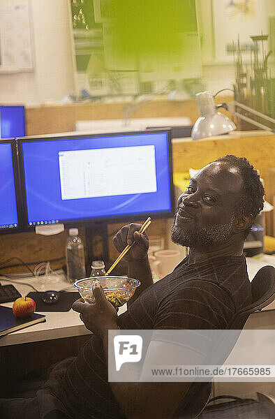 Portrait smiling businessman eating lunch at desk in office