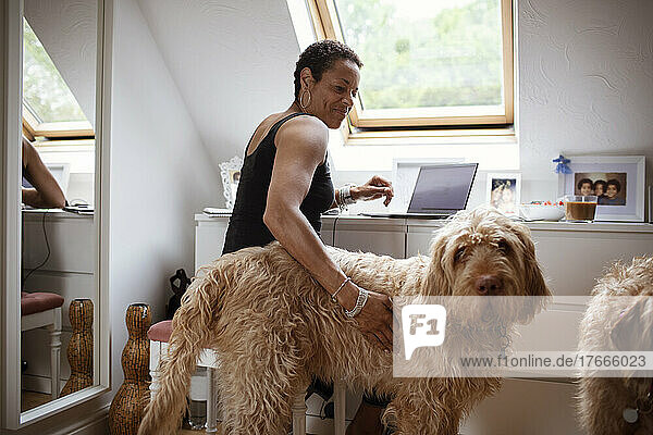 Woman petting Labradoodle dog and working from home