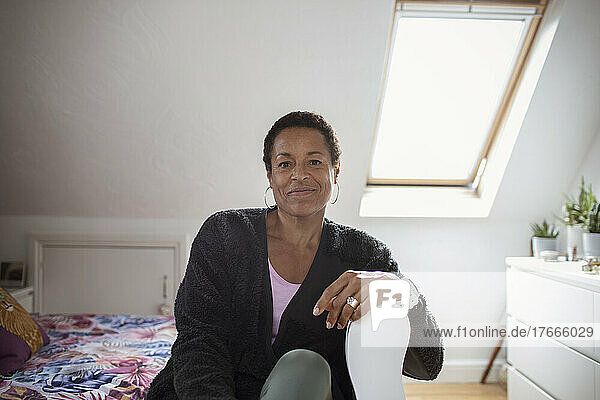 Portrait confident mature woman in sunny bedroom
