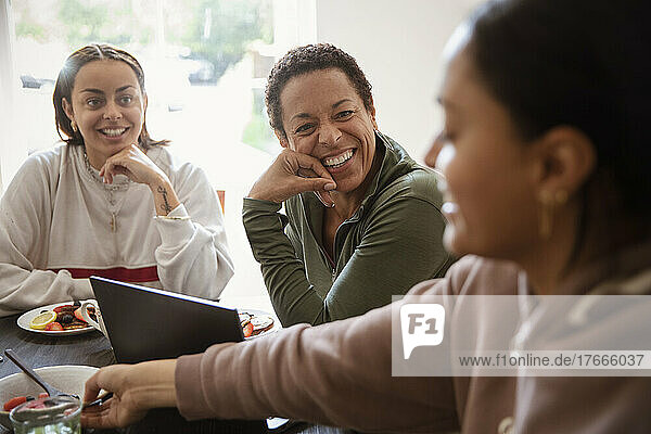 Happy mother and young adult daughters talking at home