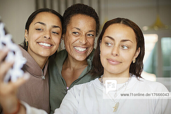 Happy mother and young adult daughters taking selfie