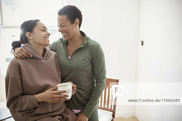 Happy mother and young adult daughter hugging at home