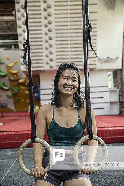 Portrait happy female rock climber training at climbing gym