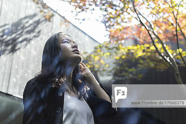 Thoughtful young woman looking up in courtyard