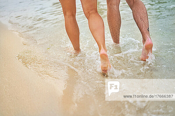 Legs of couple running in ocean surf