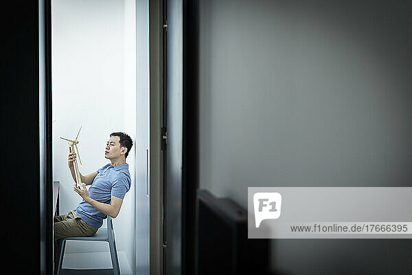 Male architect looking at wind turbine model in office doorway